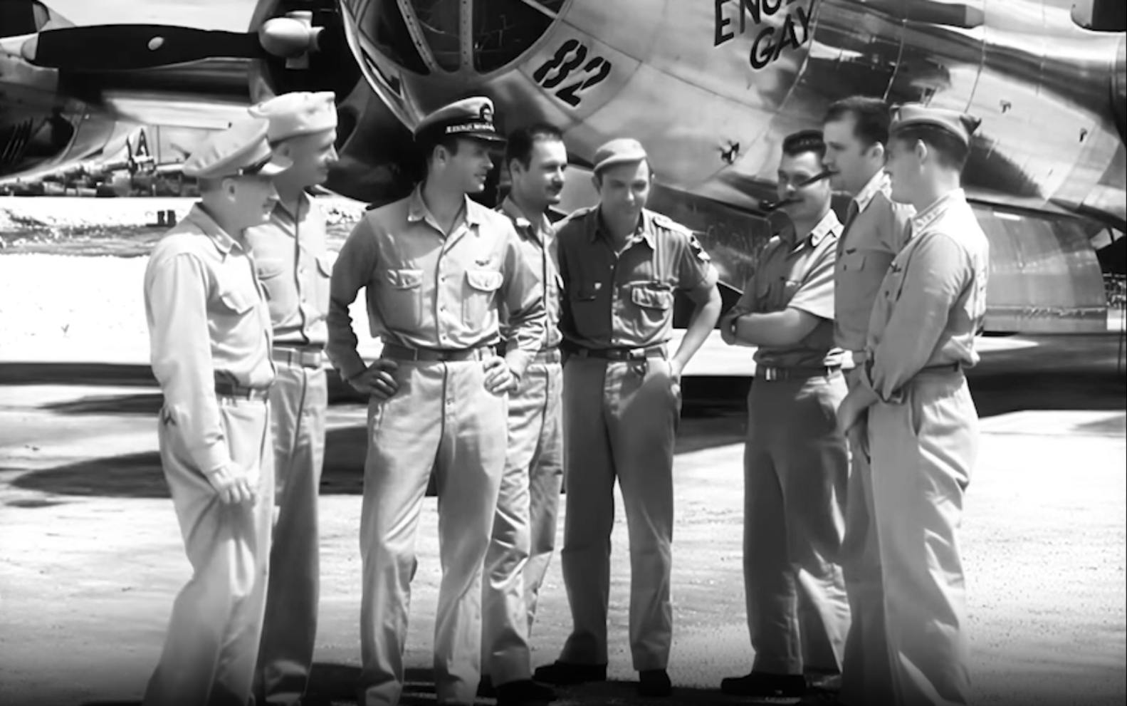 חלק מצוות ה"אנולה גיי", מפציץ B-29 (ברקע התמונה), עם שיבתם מהטלת פצצת האטום על הירושימה, יפן, אוגוסט 1945. בין המצולמים, שלושת הראשונים משמאל לימין: תא"ל תומאס פארל, מנהל פעילות השטח של "פרויקט מנהטן"; אל"מ ויליאם פרסונס, קצין החימוש האווירי במשימה; אל"מ פול טיבטס, מפקד להק 509, היחידה הצבאית האמונה על הטלת פצצות אטום. טיבטס פיקד אישית על משימת הירושימה, הטיס את המפציץ וערב הטיסה הגורלית העניק למפציץ את שמו, "אנולה גיי", על שם אימו | תמונה: ויקיפדיה.
